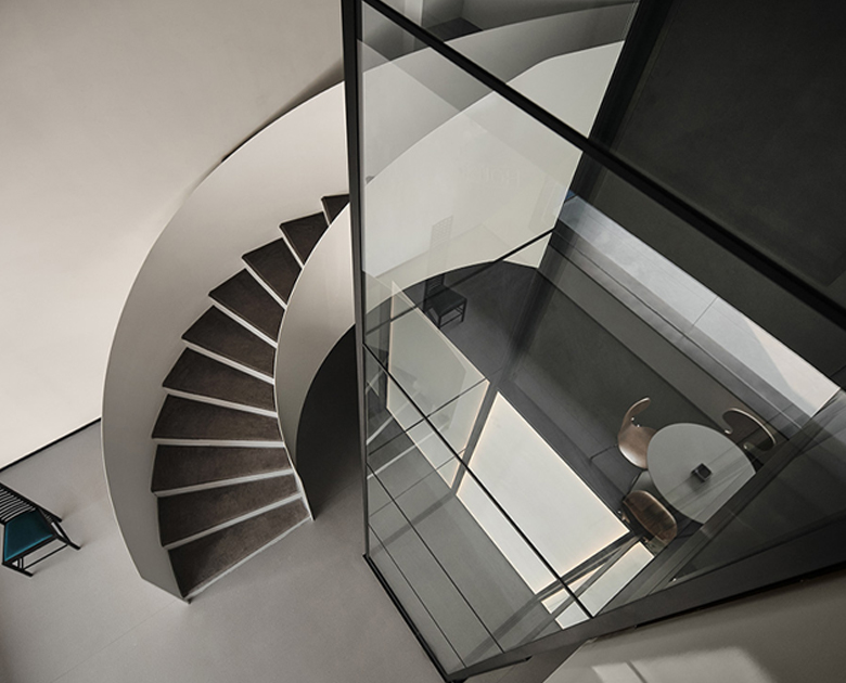 HOUSTY glass home lift beside a curved staircase